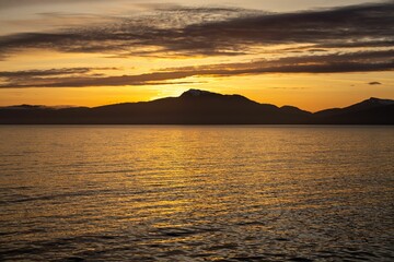 Serene sunset over sea and mountains.