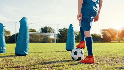 Sports field, active and child with ball, feet and athlete with energy for practice in morning....