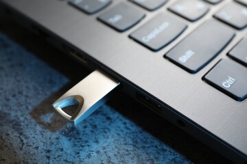 USB flash drive connected to laptop on dark grey table, closeup