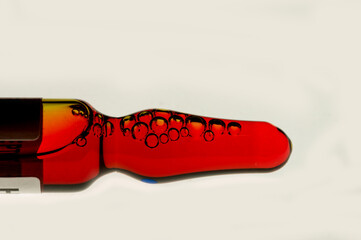 Colorful red and black ampoule on a white background. An abstract image of a medical ampoule. Vibrant red vial with black circular patterns. A bright medical container with unique design.