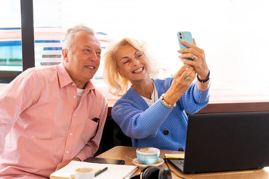 Senior russian couple taking selfie in cafe with smartphone