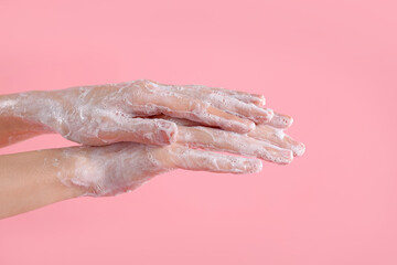 Woman washing hands with soap on light pink background, closeup
