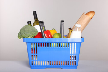 Fototapeta premium Shopping basket with different food products on gray background
