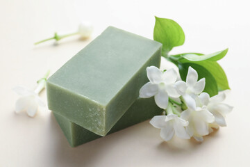Bars of soap and jasmine flowers on beige background, closeup