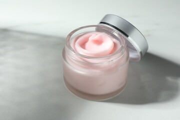 Jar of moisturizing body cream on white table, closeup. Space for text