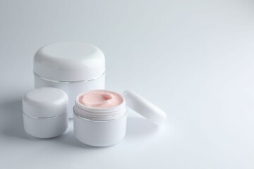 Jars of moisturizing body cream on white background