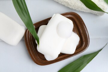 Soap bars with foam on white table, flat lay