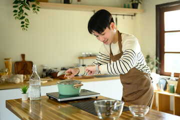Happy Asian man cooking at home with fresh ingredients