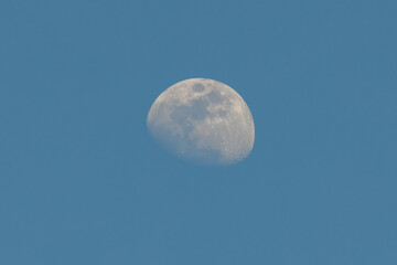Half moon shining in the blue sky during the day