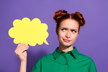 Adorable Woman in Green Shirt Holding Yellow Speech Bubble Against Purple Background Exhibiting...