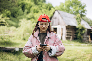 Fototapeta premium Teen girl using smartphone outdoors in countryside, copy space.