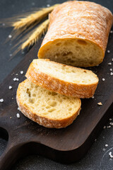 Ciabatta bread on wooden board on black background.
