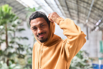 Young man wearing hoodie adjusting hood in urban setting