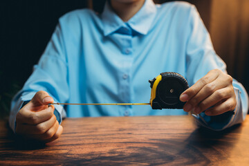 Woman Measuring Length with Tape Measure in Blue Shirt Close-Up, Focus on Hands and Measuring Tool