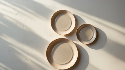 Fototapeta premium Flat lay of three differently sized plates on a background. Top-down perspective. Natural hues of the plates. Grainy texture pattern on the plates.