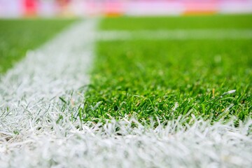 Close-up view of corner line, football, soccer field, with sharp white markings on well-maintained green grass.