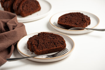 Slices of rich double chocolate pound cake on white plates. Front view