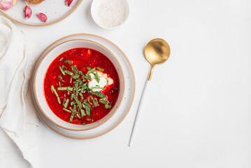 Traditional Ukrainian borscht with sour cream, garlic and rye bread on white table. Top view