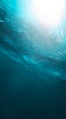 A tranquil underwater scene in soft blue hues with sunbeams filtering down from the surface