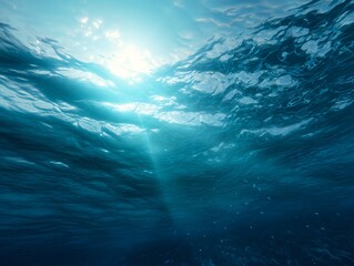 A tranquil underwater scene in soft blue hues with sunbeams filtering down from the surface
