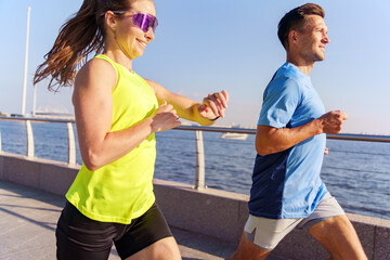 Joyful morning joggers enjoying an energizing run along a serene waterfront pathway at sunrise