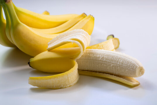 Studio shot of bunch of ripe bananas with one partially peeled