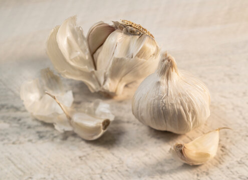 Pealed and whole garlic on rough white board