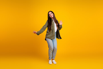 Young woman posing joyfully in casual fashion against a vibrant yellow background, expressing happiness and a trendy lifestyle
