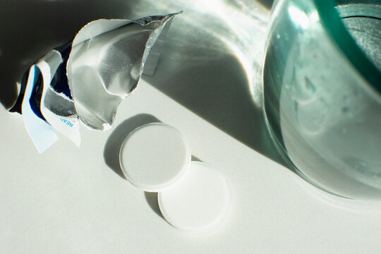 Close-up of effervescent antacid tablets next to glass of water