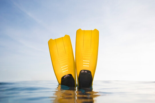 Personal perspective of feet in yellow flippers on calm sea