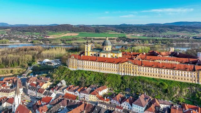 Melk in Lower Austria. Old town with active Benedictine abbey, monastery and church in Baroque style on the rocky hill and Danube river. Aerial drone 4K video in sunset light