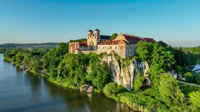 Tyniec near Krakow, Poland. Active Benedictine abbey, monastery and church on the rocky cliff and Vistula River. Aerial 4K video, summer, sunset light. Blue sky with copy space
