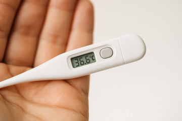 Checking Temperature: A detailed shot of a digital thermometer held by hand. This medical instrument displays an accurate temperature reading.