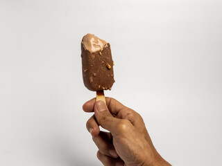 Hand holding a delicious chocolate ice cream bar against a white backdrop