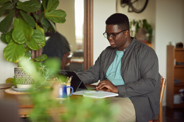 Young African man working remotely from home on a tablet