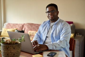 Young African man working remotely from home on a laptop