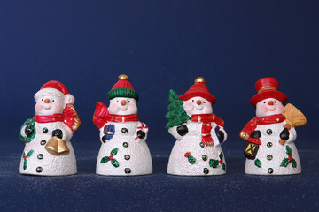 Four snowmen in red hats over dark blue background