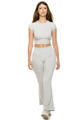 Plakat Young woman walking confidently toward camera in gray outfit, white background.