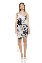 Elegant young woman in floral one-shoulder dress and white heels posing frontally, studio shot on...