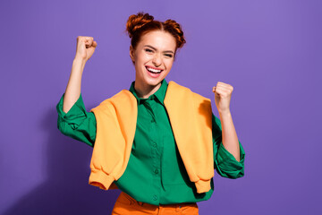 Adorable Confident young woman celebrating success in vibrant casual outfit against purple backdrop