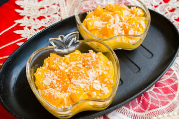 Homemade Mango Mousse in Apple Shaped Glass Bowl – Healthy Dessert on Rustic Tray with Red Background . tropical fruit dessert ideal for culinary blogs, summer recipes, and gourmet presentations.