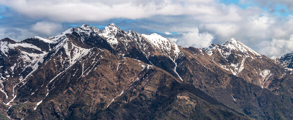 Sweeping panorama showcasing the rugged alpine beauty of Pizzo Alto, Monte Rotondo, and their surrounding peaks under a dynamic cloudy sky in the Lombardy Prealps, Italy