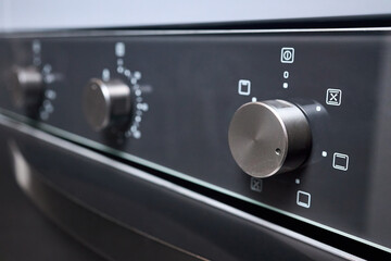 Digital kitchen oven with convection mode and temperature selectors on gas cooker hob stove selective focus close up shot.