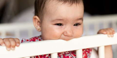 baby nibbling on his crib with copy space.