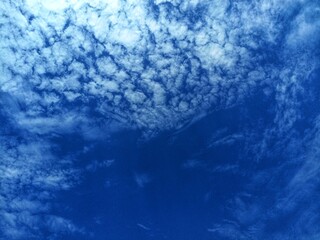 Blue sky background with white clouds on a warm summer day