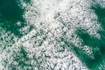 aerial perspective of foam of a dynamic breaking wave, top down view drone photography