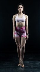 Fototapeta premium Confident fitness model posing on black background showing muscles 