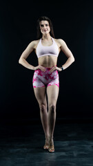 Obraz premium Confident fitness model posing on black background showing muscles 