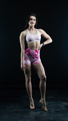 Obraz premium Confident fitness model posing on black background showing muscles 