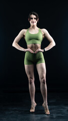 Obraz premium Confident fitness model posing on black background showing muscles 